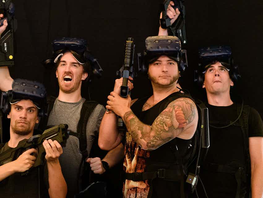 Group of men cheering with vr goggles and guns